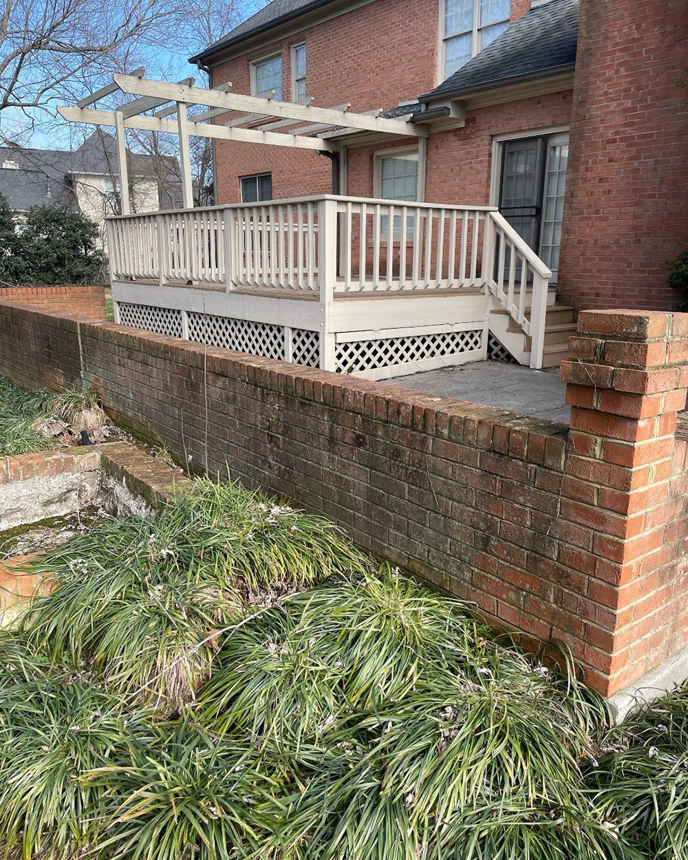 There is a deck with stairs leading up to it next to a brick wall