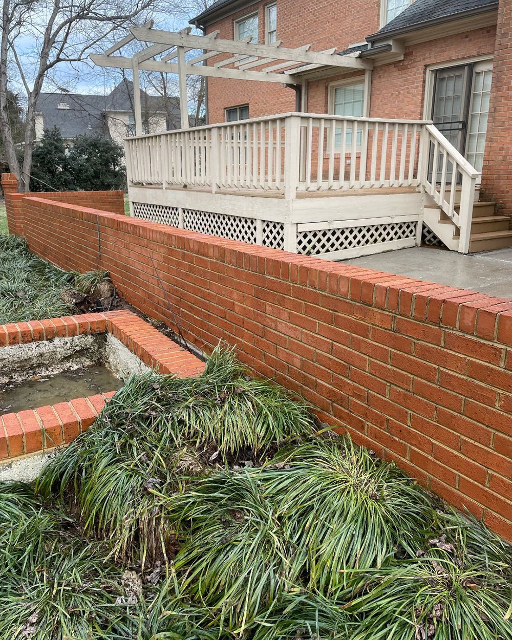 A brick wall leading to a deck with a white railing and stairs