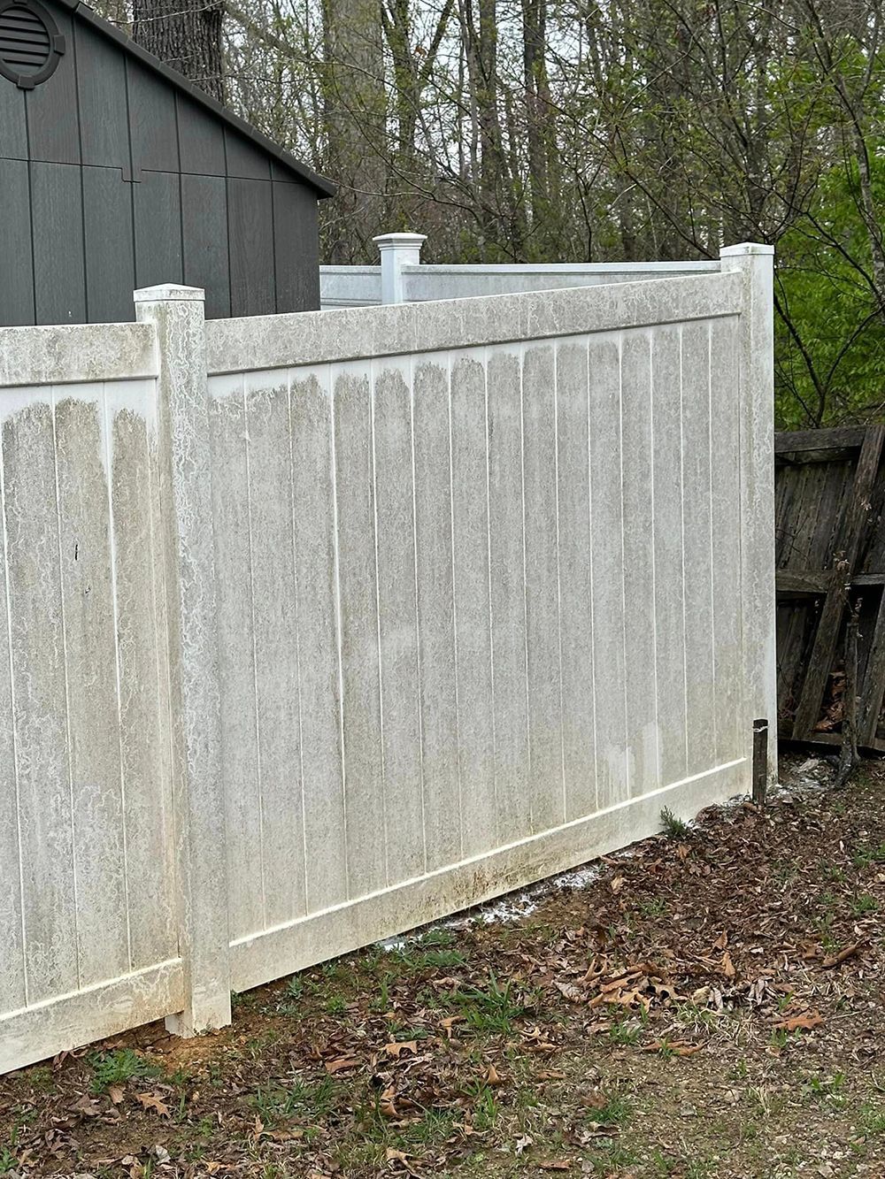 A white vinyl fence is sitting in the middle of a yard