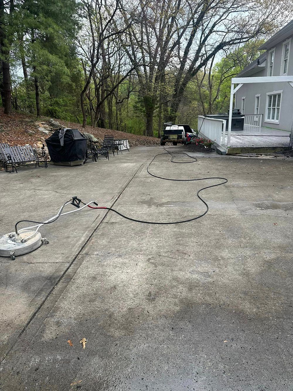 A concrete driveway with a hose attached to it and a house in the background