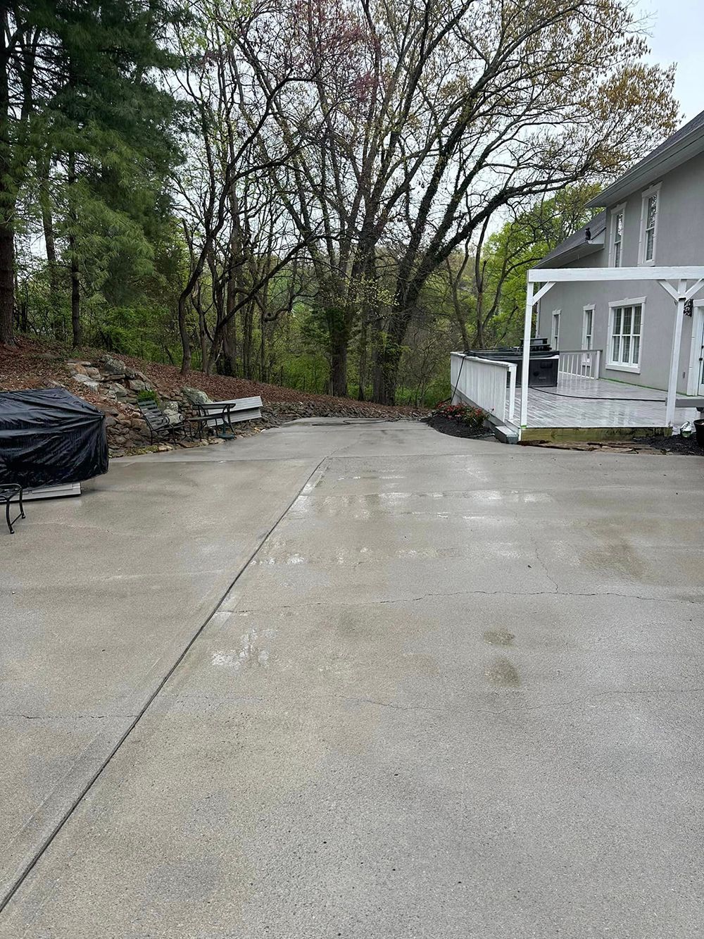 A concrete driveway leading to a house with trees in the background