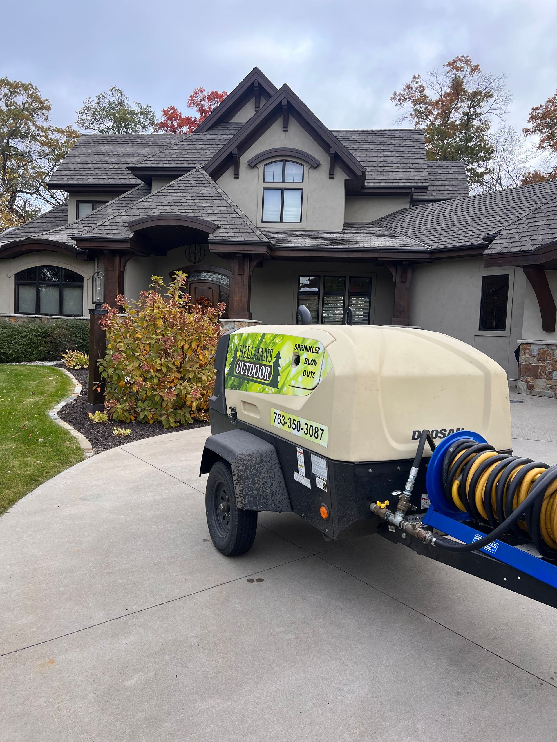 Blue pressure washer trailer on a driveway in front of a large house