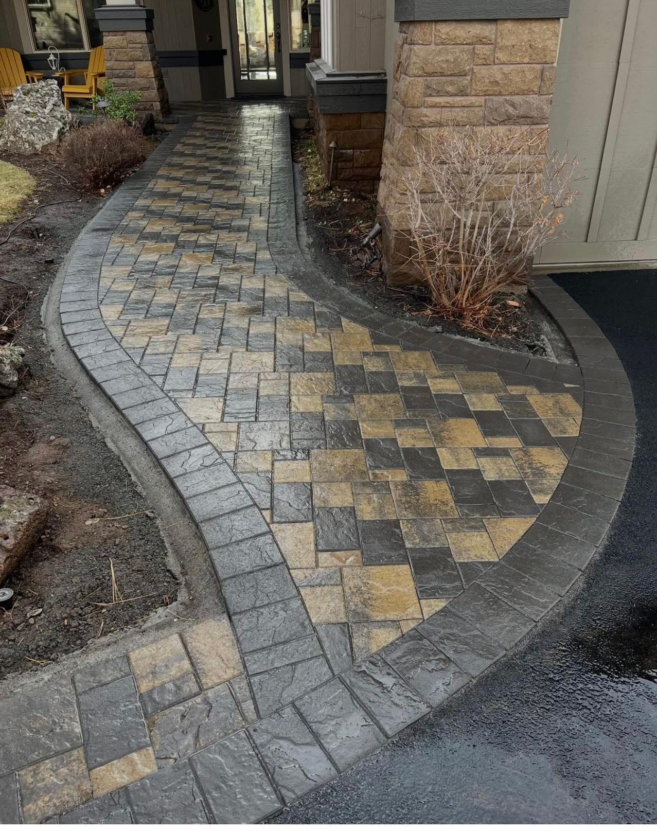 Curved stone paver walkway with gray and tan patterns leading to a house entrance