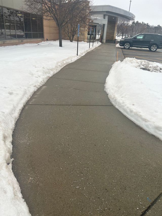 Snow-lined sidewalk leading to a building entrance on an overcast day