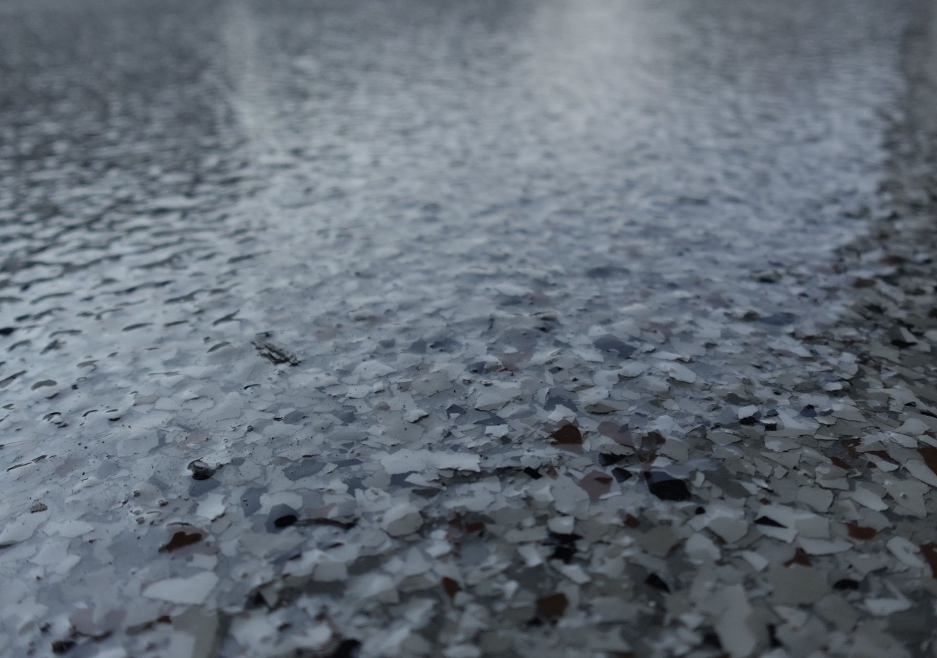 Close-up of gray pebbled ground with a wet, rippled surface in the background