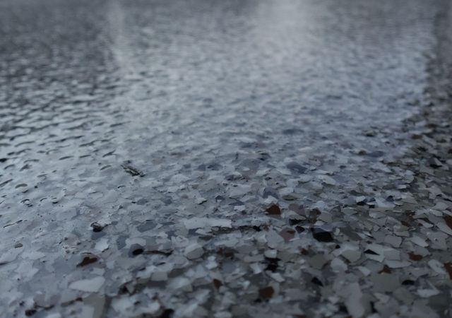Close-up of wet gray gravel with rippling water reflections