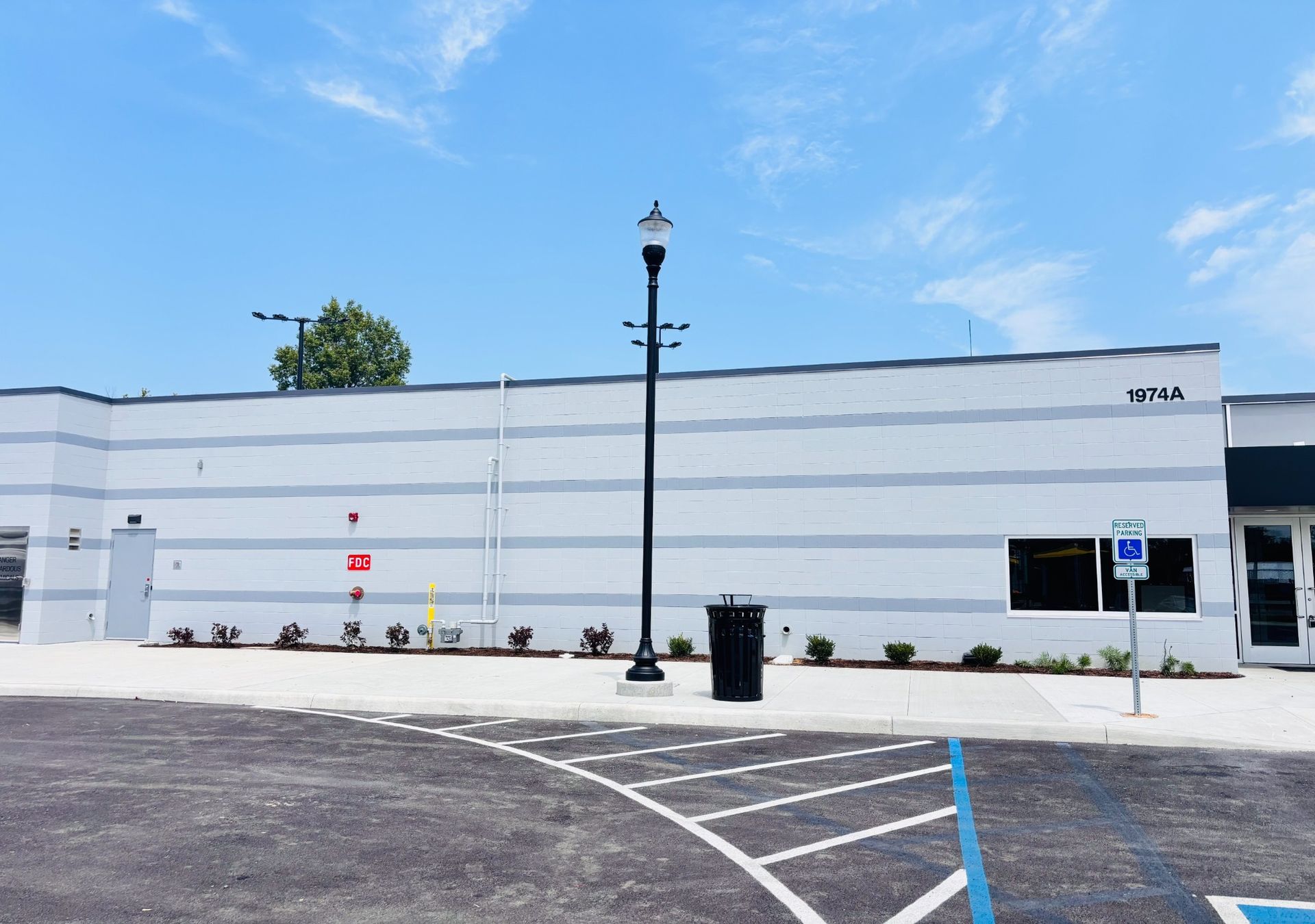 White commercial building with black lamp post, blue sky, and empty parking lot