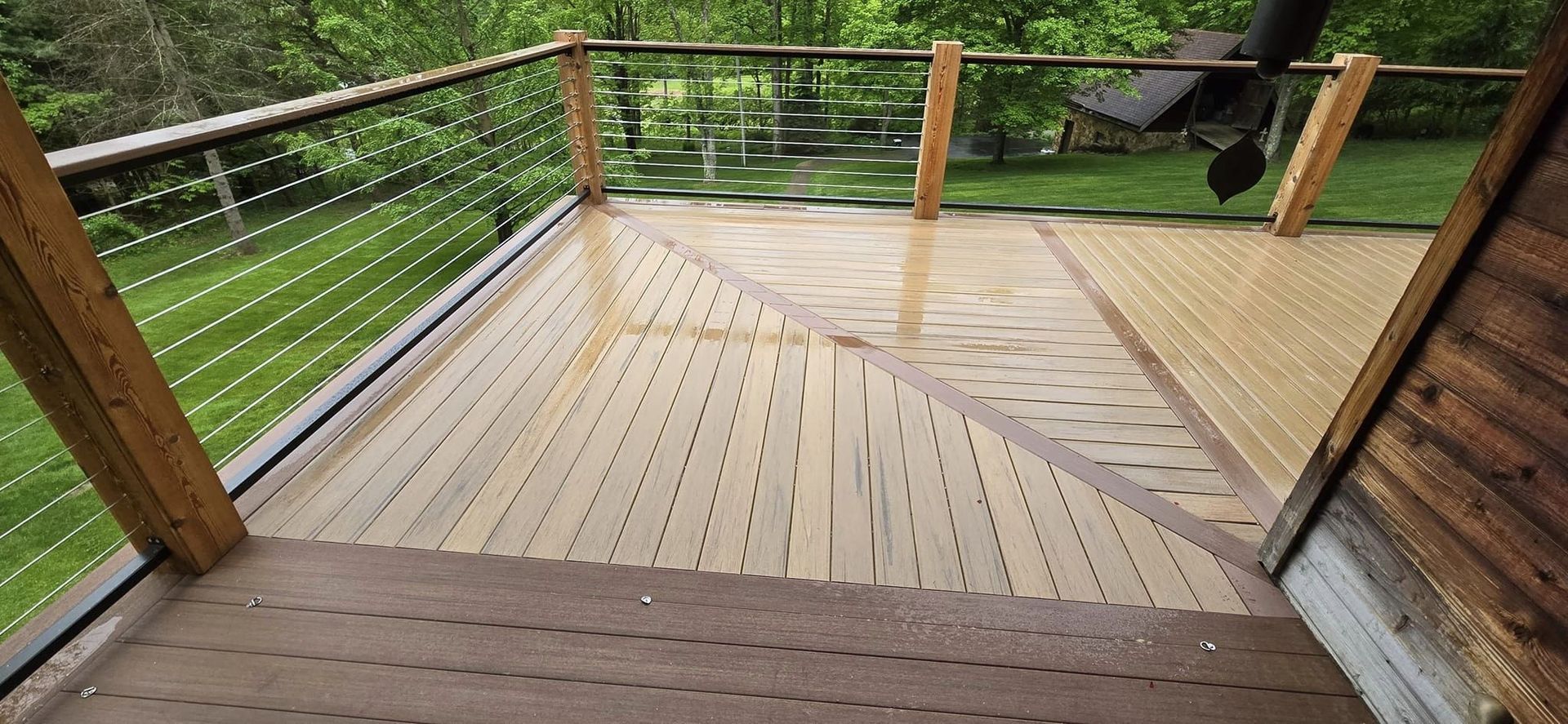 A wooden deck with a metal railing and stairs leading up to it.