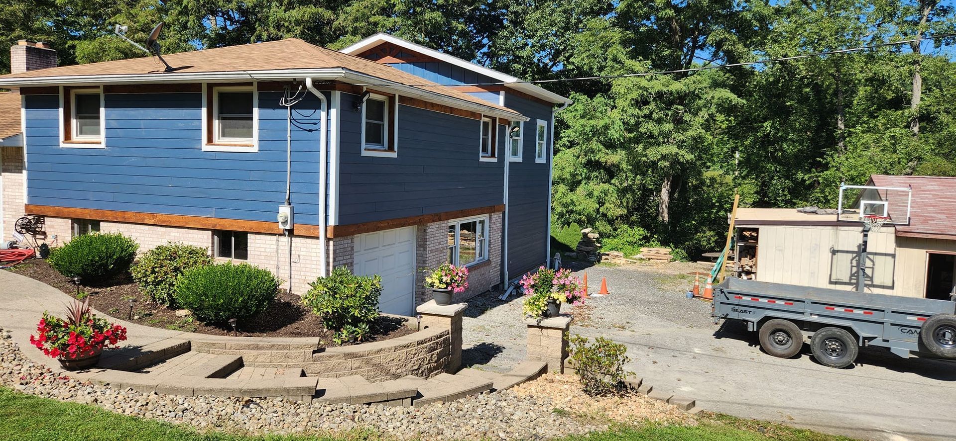 A blue house with a trailer parked in front of it.