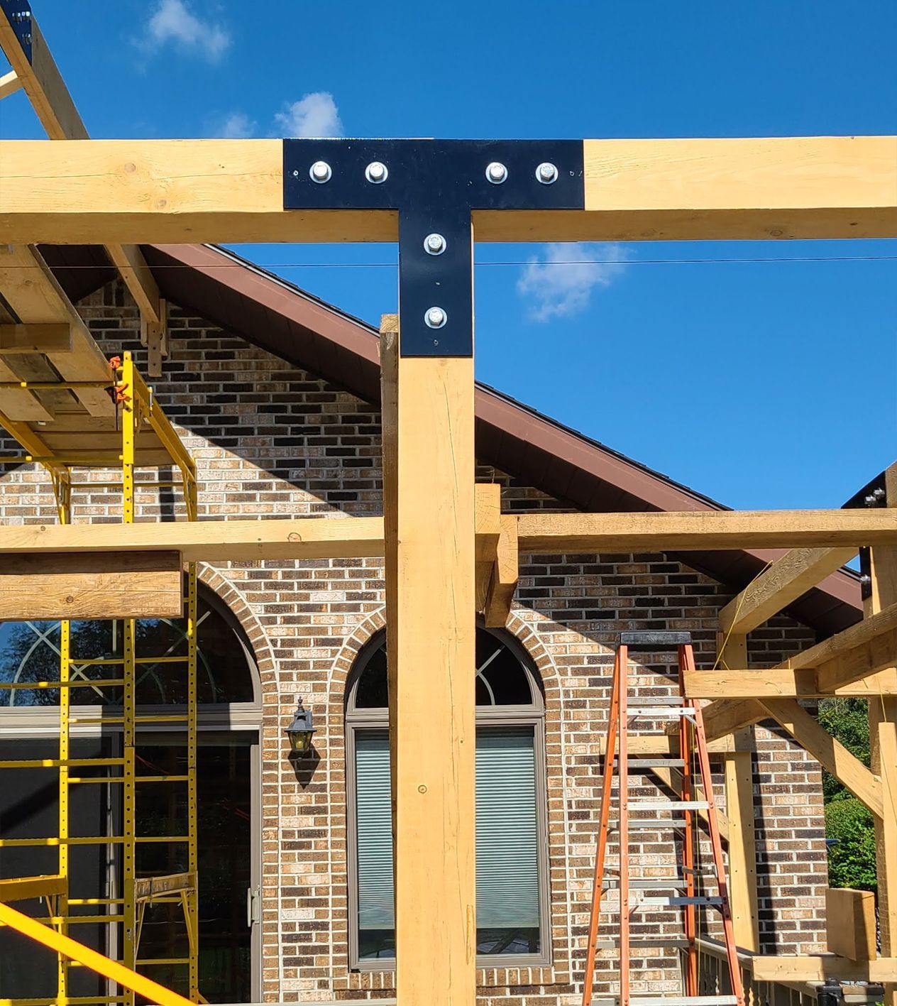 A wooden structure is being built in front of a brick house