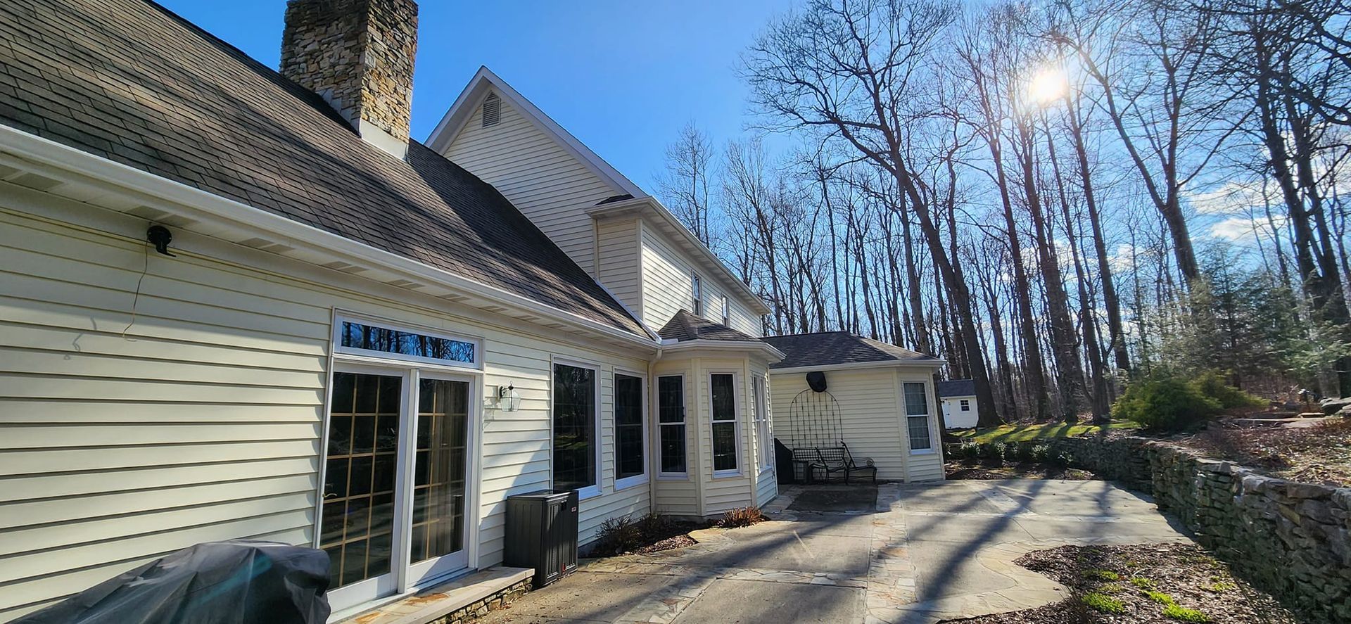 A large white house with a lot of windows is surrounded by trees on a sunny day.
