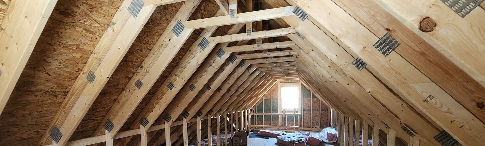 An attic under construction with wooden beams and insulation.