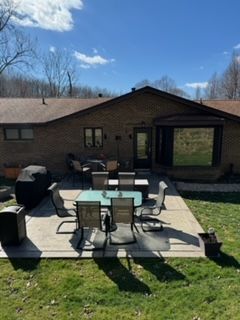 A patio with a table and chairs in front of a brick house.