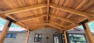 The roof of a wooden gazebo with a brick house in the background.