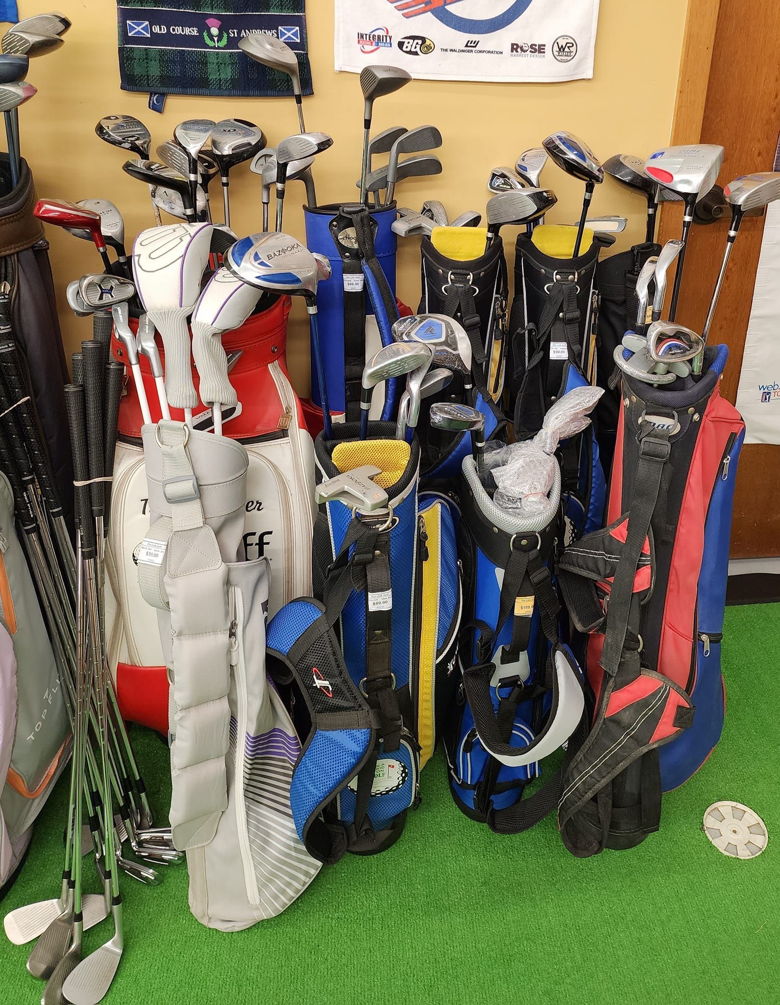 a bunch of golf clubs are stacked on top of each other on a green carpet .