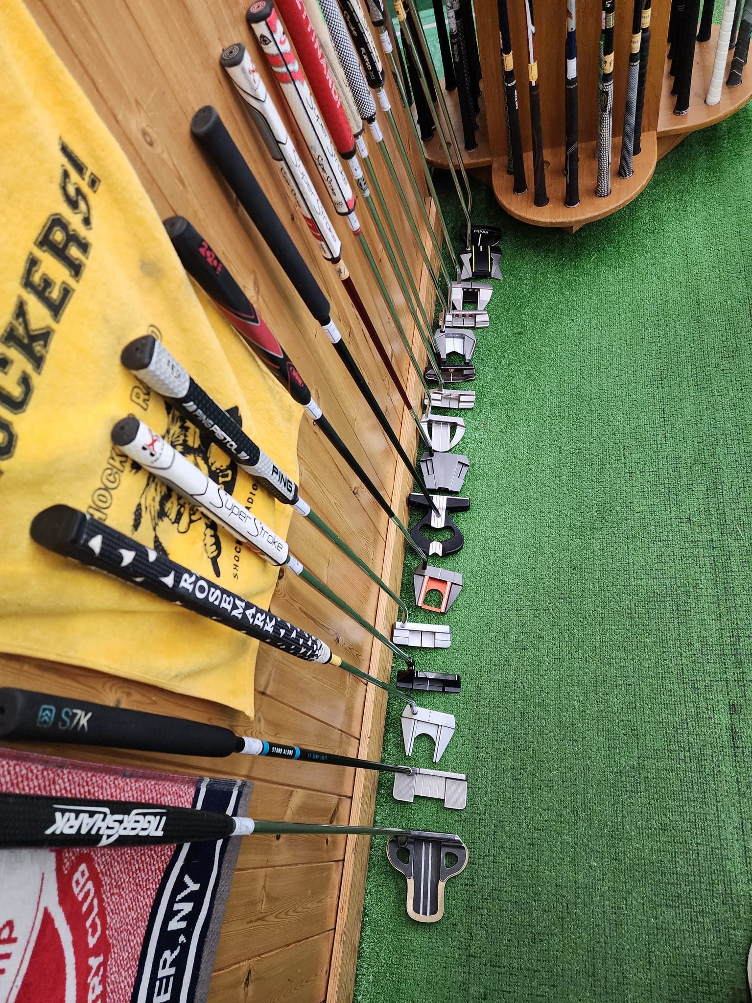 a bunch of golf clubs are hanging on a wall in a store .