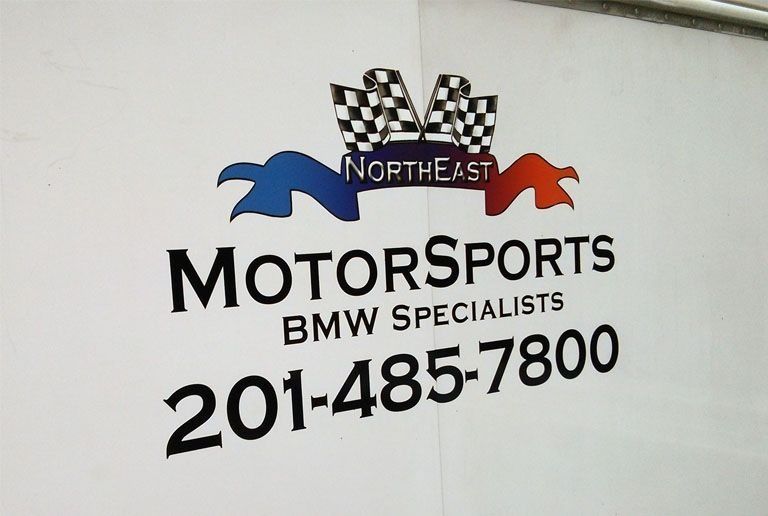 Logo for Northeast Motorsports, a BMW specialist, with checkered flags and phone number 201-485-7800.