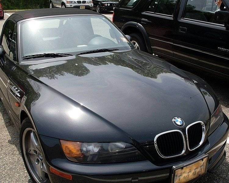 Black BMW Z3 convertible parked in a lot, hood reflecting sunlight.
