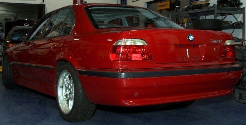 Red BMW 5-series sedan, rear view, parked inside a garage.
