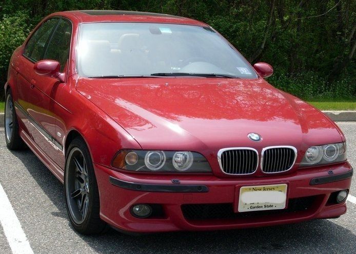 Red BMW sedan parked in a parking lot, front view.