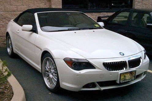 White BMW convertible, parked outdoors with a black roof and shiny chrome wheels.