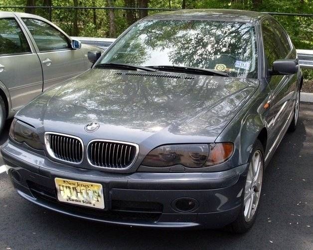 Gray BMW sedan with blacked-out headlights parked outdoors; New Jersey license plate.
