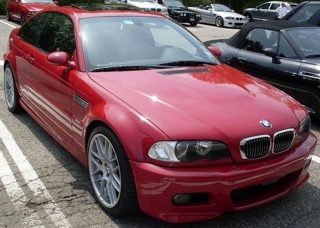Red BMW M3 coupe parked in a lot with other cars.