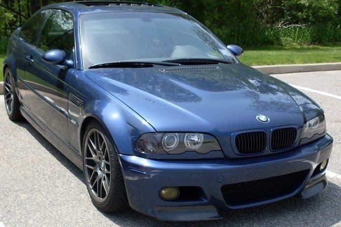Blue BMW coupe parked outside, with blacked-out front grille, wheels, and headlights.