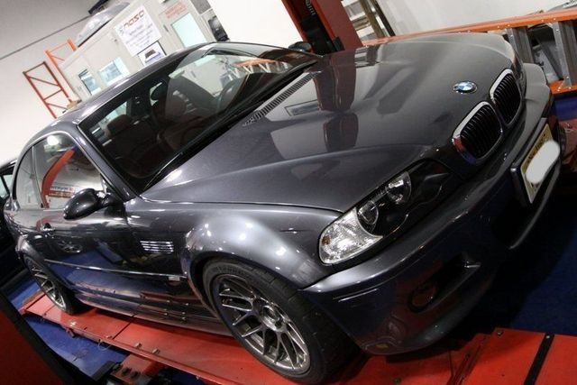 Dark gray BMW M3 coupe on a dynamometer; in a garage setting.