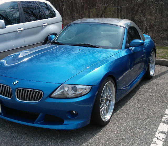Blue BMW Z4 roadster with silver roof, parked in a lot.