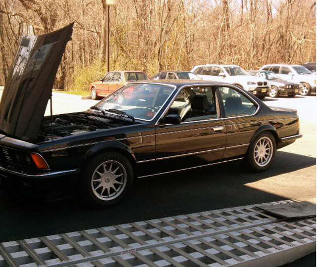 Black BMW coupe with hood open parked outdoors.