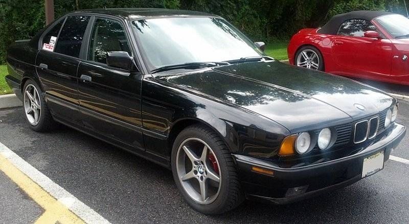 Black BMW sedan parked, next to a red convertible.