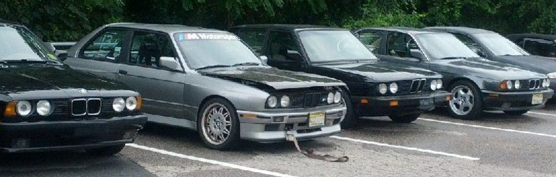 Several BMW cars are parked in a row in an outdoor setting.