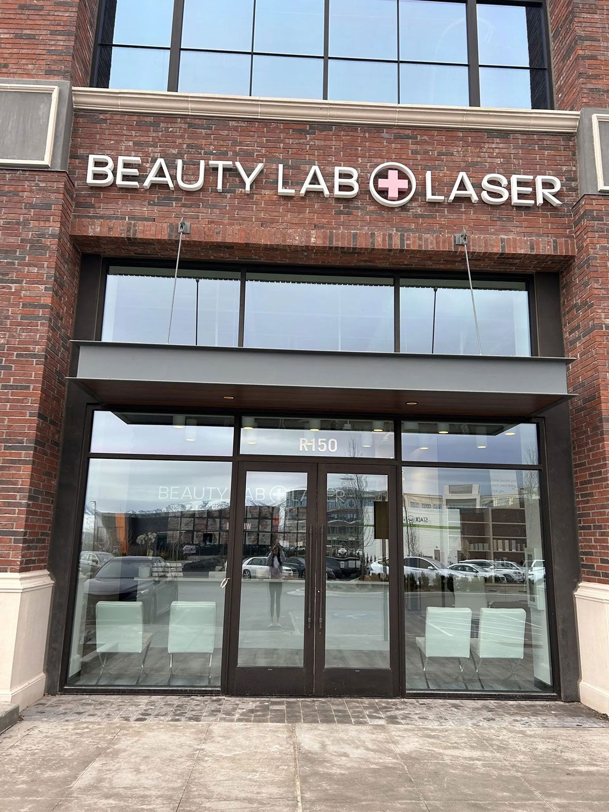 Storefront of Beauty Lab + Laser with brick walls, large glass windows, and a white sign above the entrance.