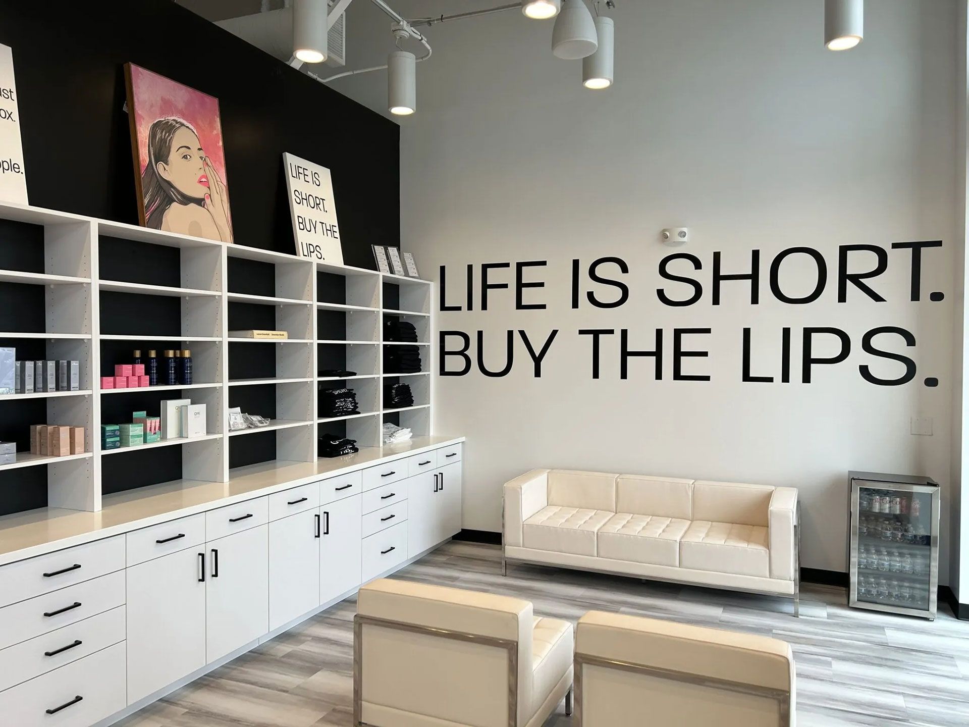 Modern aesthetic clinic with white shelving, minimalist seating, and wall text reading 