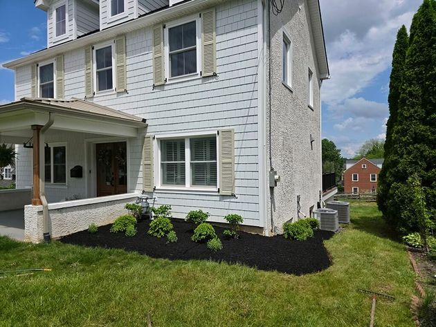 Grassy front yard with stone walkway between two houses on a cloudy day