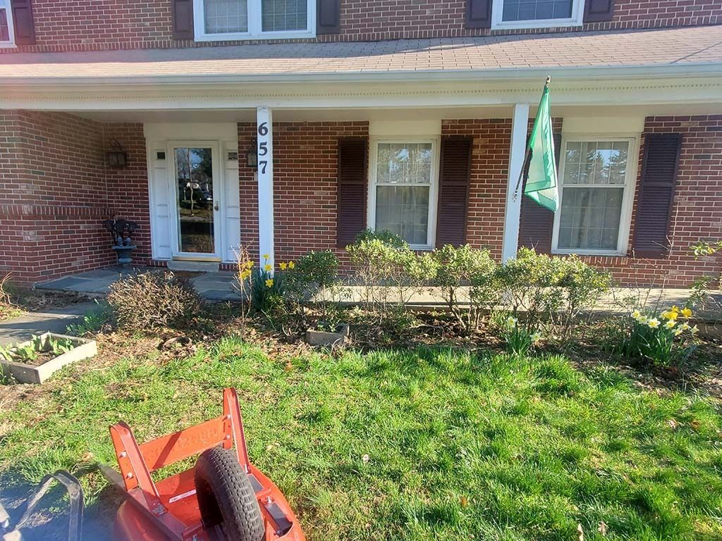Brick house front porch with white columns, windows, and green lawn in front