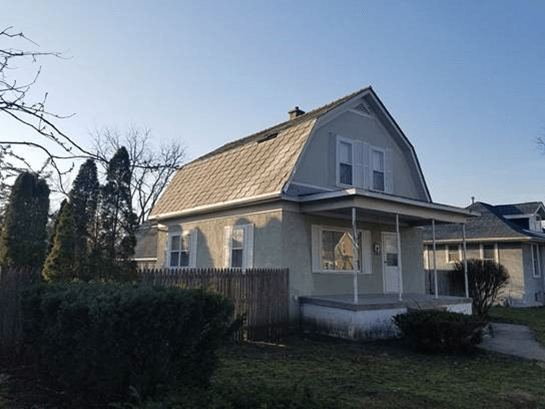 A house with a porch and a fence in front of it