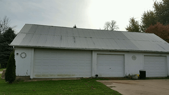 A white garage with three garage doors and a gray roof.