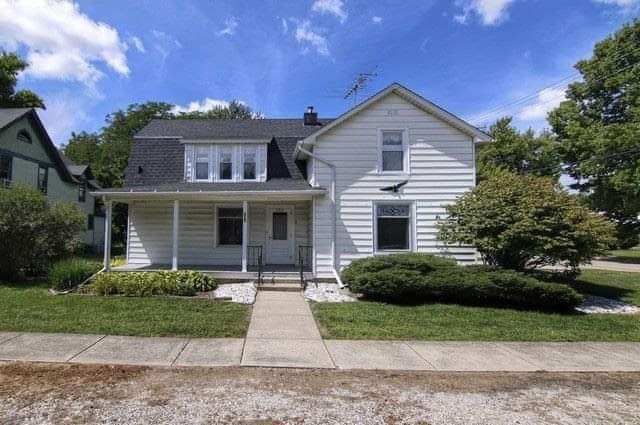 A white house with a black roof and a porch