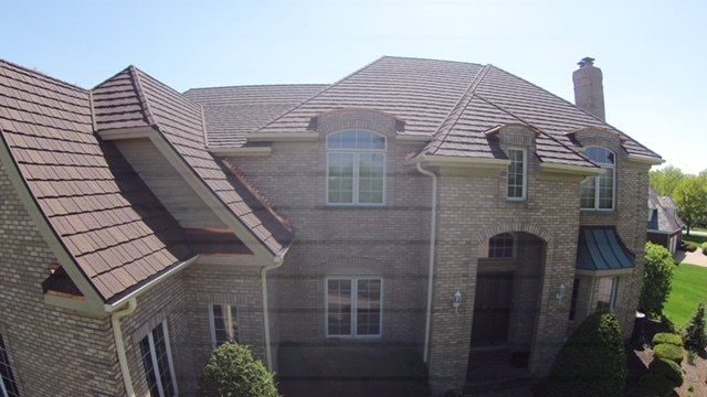 An aerial view of a large brick house with a brown roof