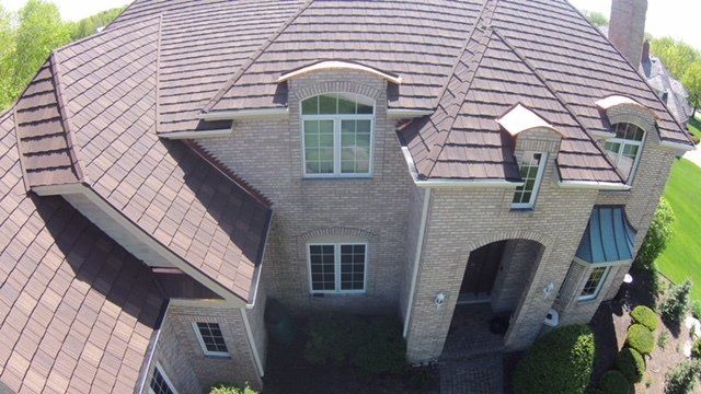 An aerial view of a large brick house with a brown roof