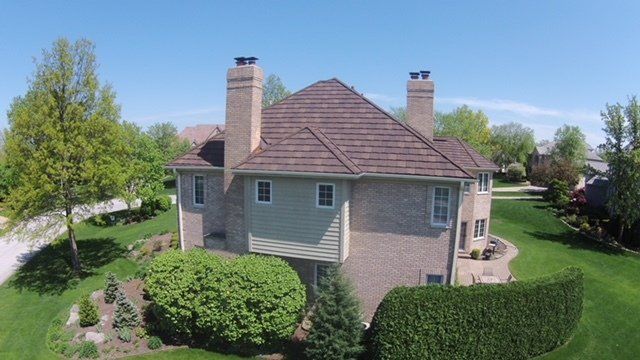 An aerial view of a large brick house with a large lawn in front of it.