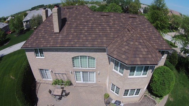 An aerial view of a large brick house with a brown roof.