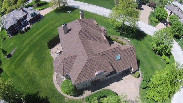 An aerial view of a house with a brown roof in a residential area.