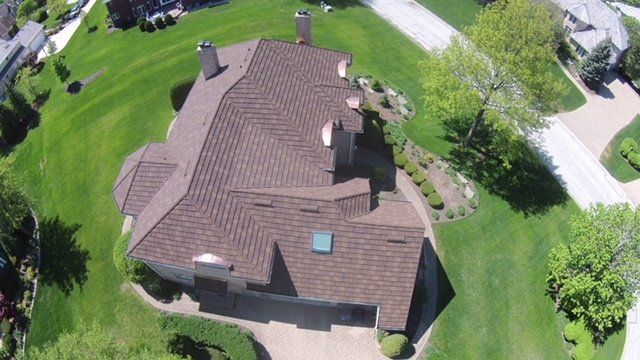 An aerial view of a house with a brown roof in a residential area.