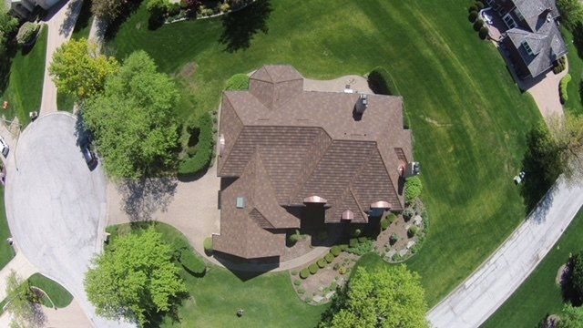 An aerial view of a house with a brown roof in a residential area.