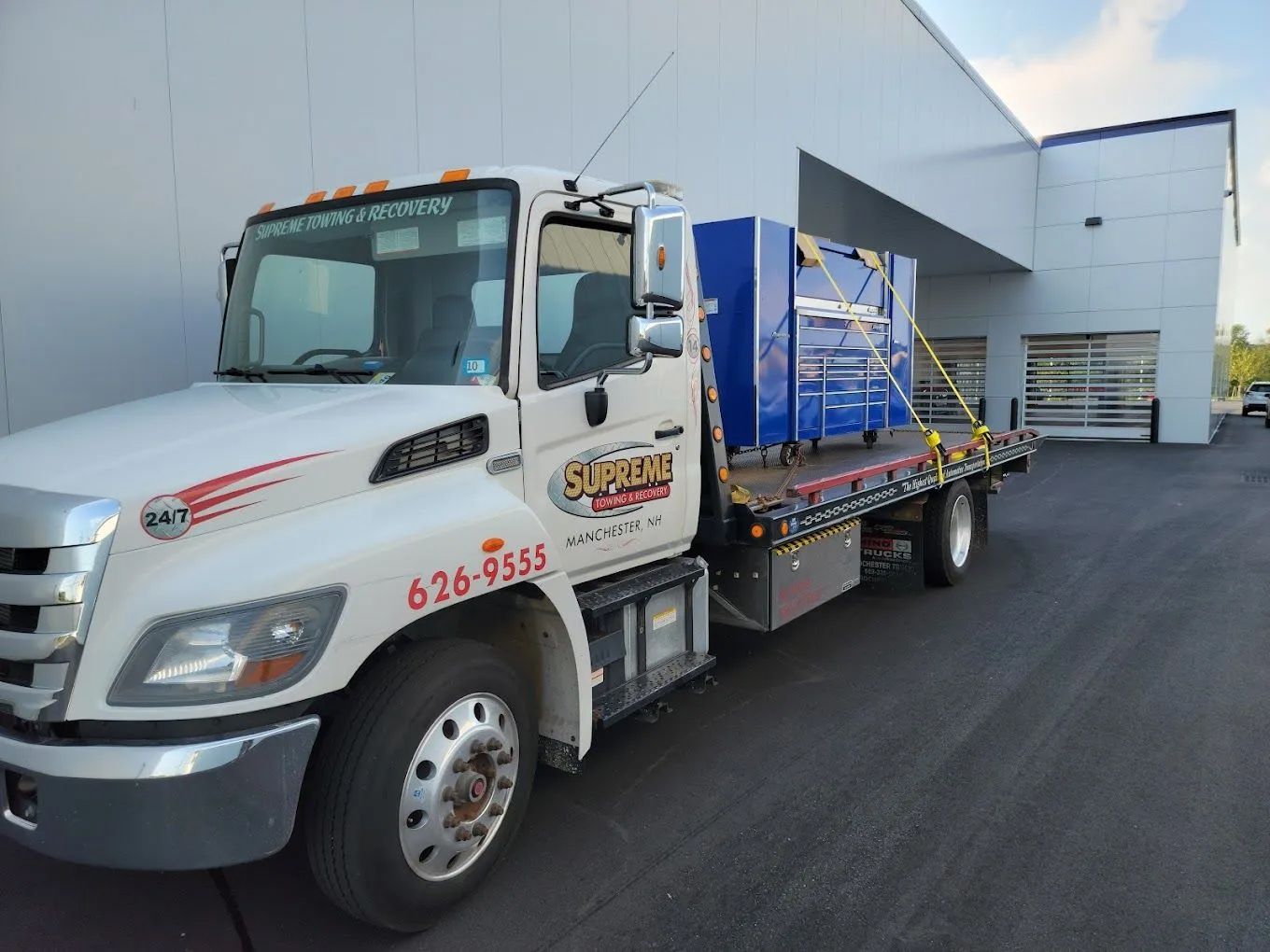 A white tow truck is parked in front of a building.