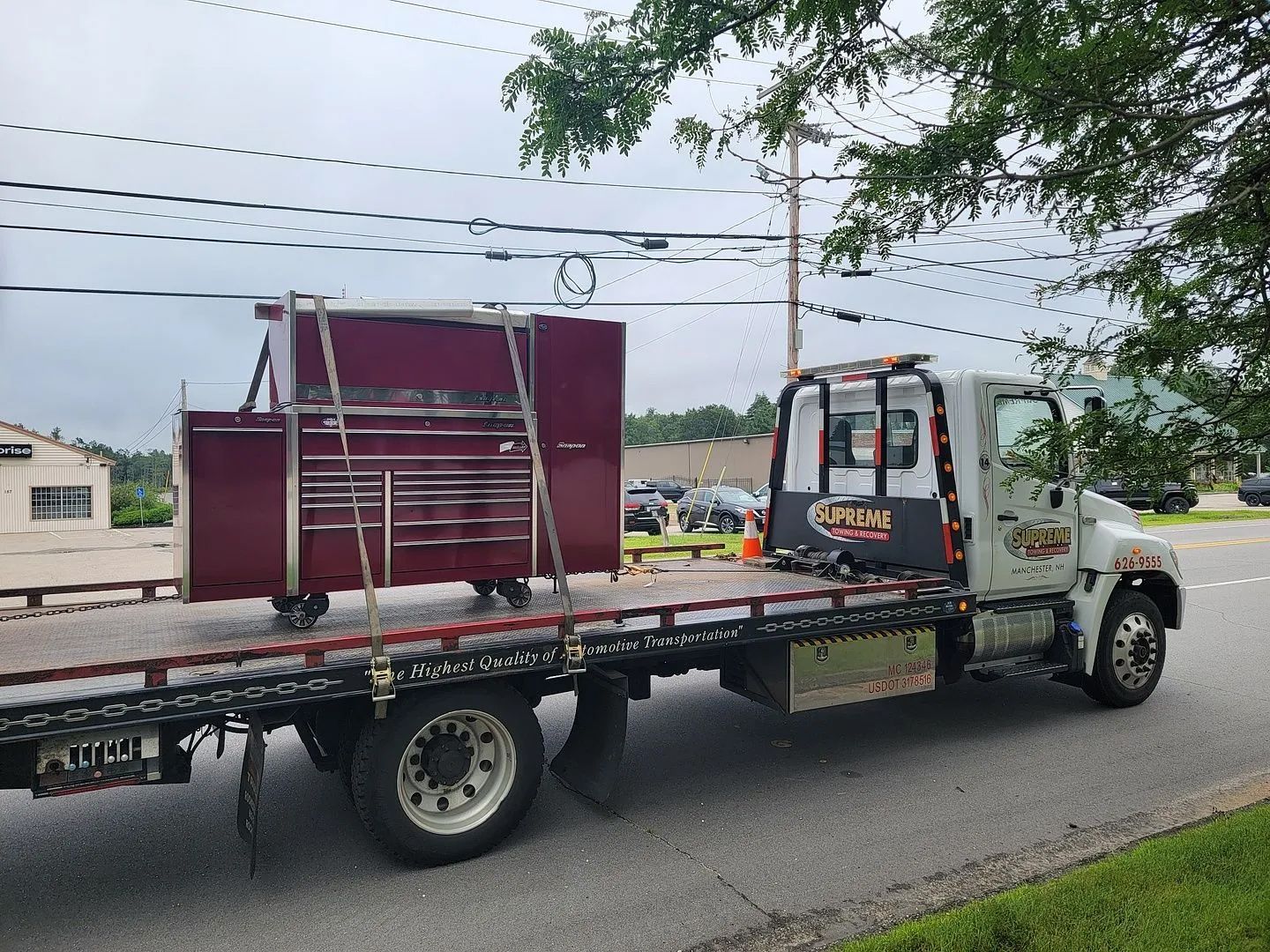 A tow truck is carrying a toolbox on the back of it.