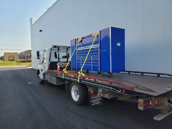 A tow truck with a blue toolbox on the back is parked in front of a building.